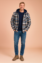 Men’s hooded plaid flannel jacket with quilted lining, chest pocket, and button-down closure styled with blue jeans and taupe suede lace-up boots.