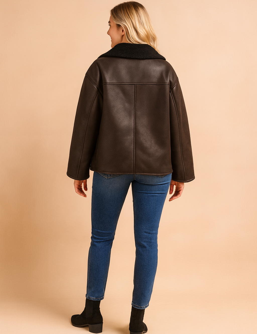 Back view of a dark brown shearling-lined jacket with wide sleeves, straight hem, and panel seam detailing, featuring a soft textured interior collar and smooth leather-look exterior.