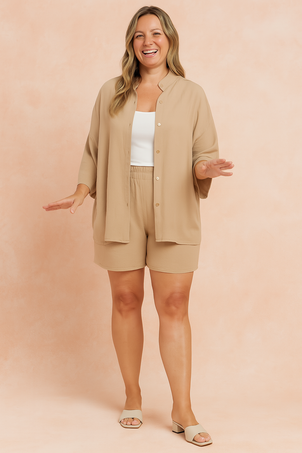 Beige oversized button-up shirt with dropped shoulders paired with matching high-waisted loose shorts in soft, flowy fabric; styled over a white cropped tank top.
