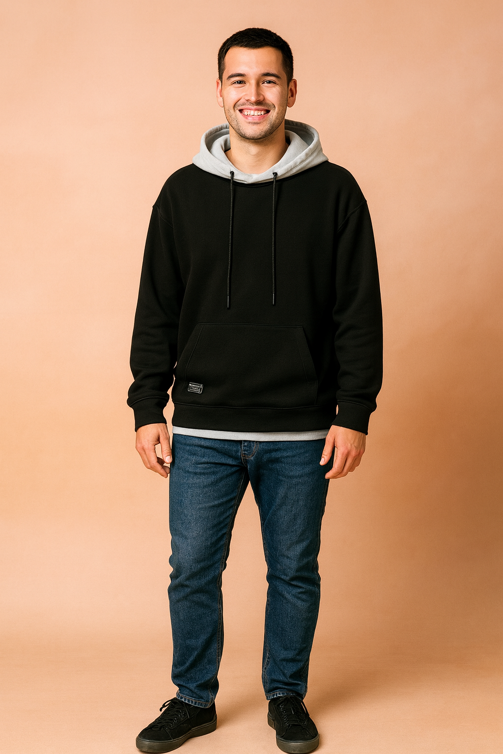 Men’s casual black hoodie with light gray hood lining, paired with blue slim-fit jeans and black sneakers.