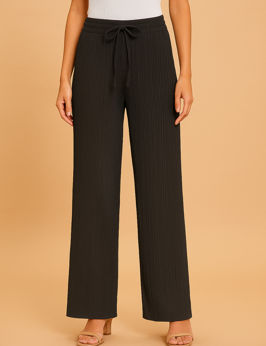 Black pleated wide-leg pants featuring a drawstring waistband and a soft ribbed texture, styled with beige heeled sandals and a tucked-in white tank top.