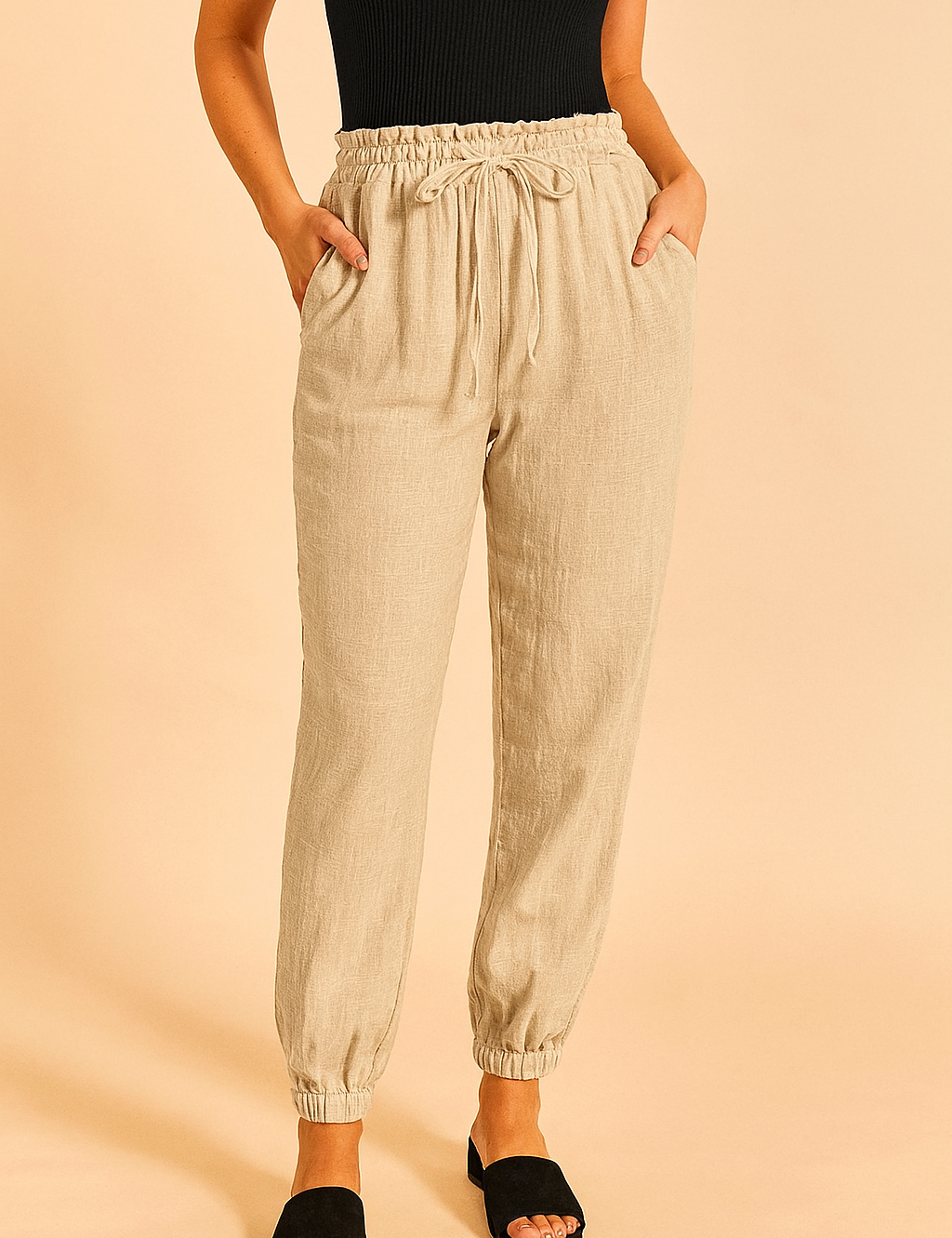 High-waisted beige drawstring jogger pants with a grid-textured finish, featuring an elastic waistband and ankle cuffs, styled with side pockets and a relaxed fit.