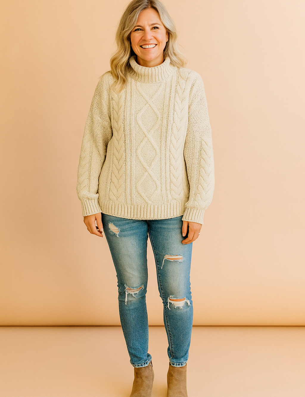 Cream cable-knit turtleneck sweater with diamond and braided patterns, paired with distressed skinny jeans and black ankle boots.