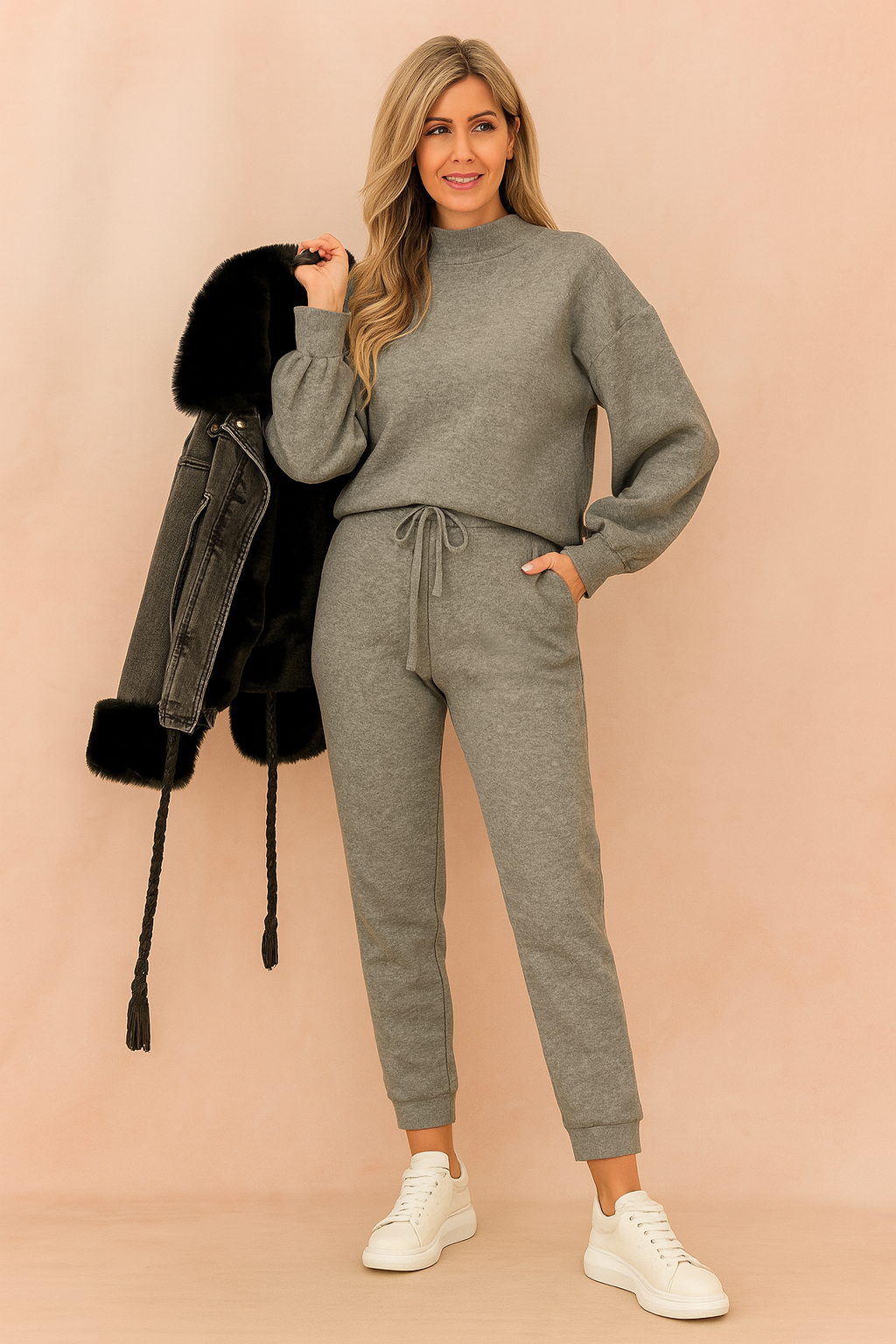 Two-piece heather gray lounge set featuring a relaxed-fit long-sleeve sweatshirt and high-waisted drawstring jogger pants in soft brushed fleece, paired with white sneakers and a black fur-lined denim jacket
