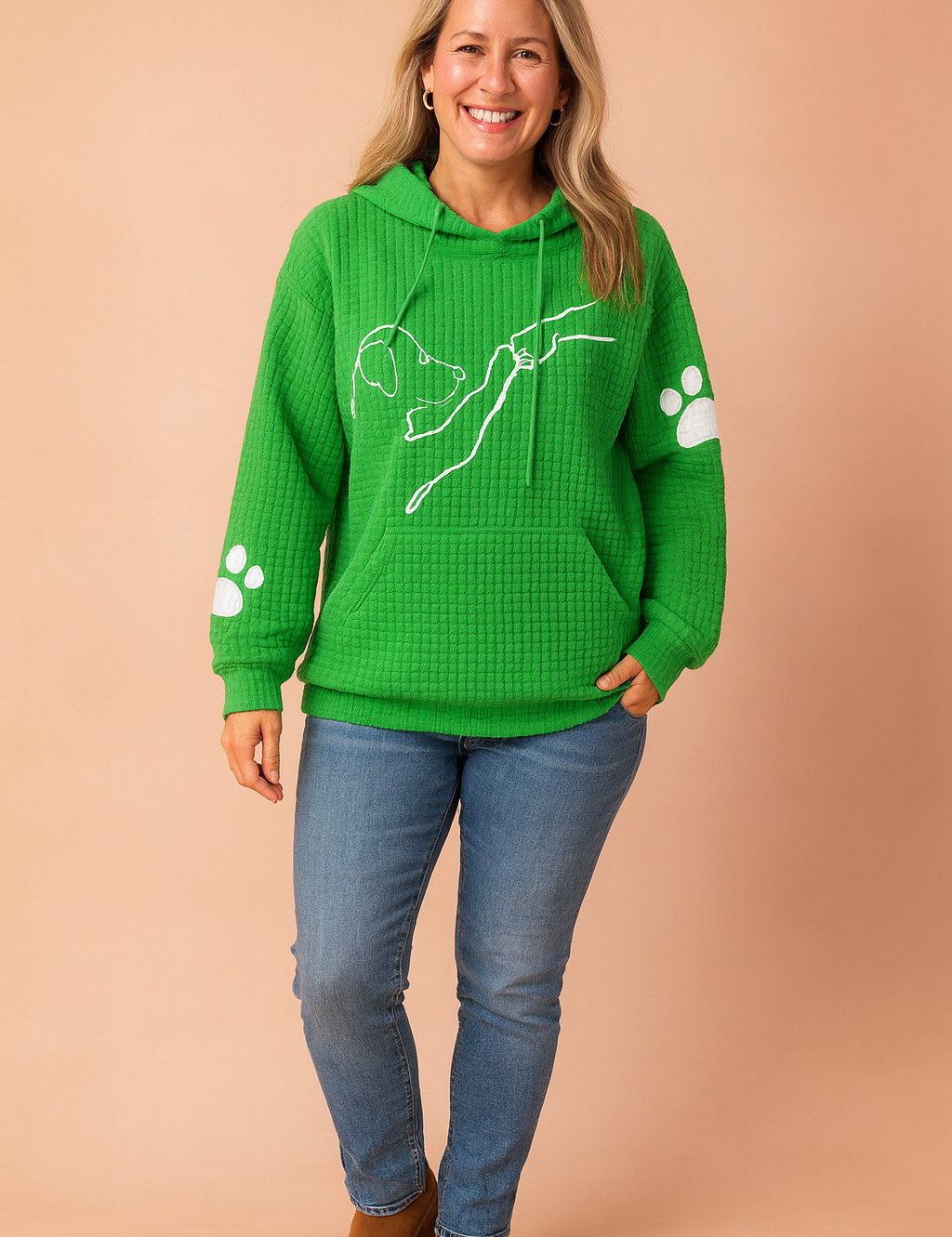 Green waffle-knit hoodie with front kangaroo pocket, featuring a white line art print of a dog reaching for a hand on the chest and white paw prints on each sleeve.