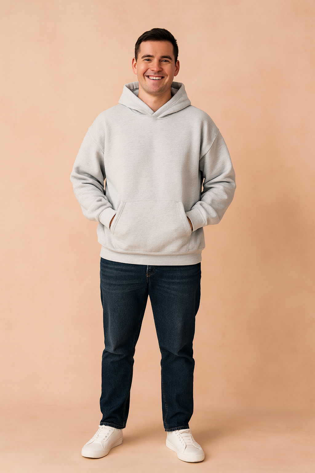 Light gray oversized hoodie with kangaroo pocket and ribbed cuffs, styled with dark blue jeans and white sneakers for a relaxed casual look.