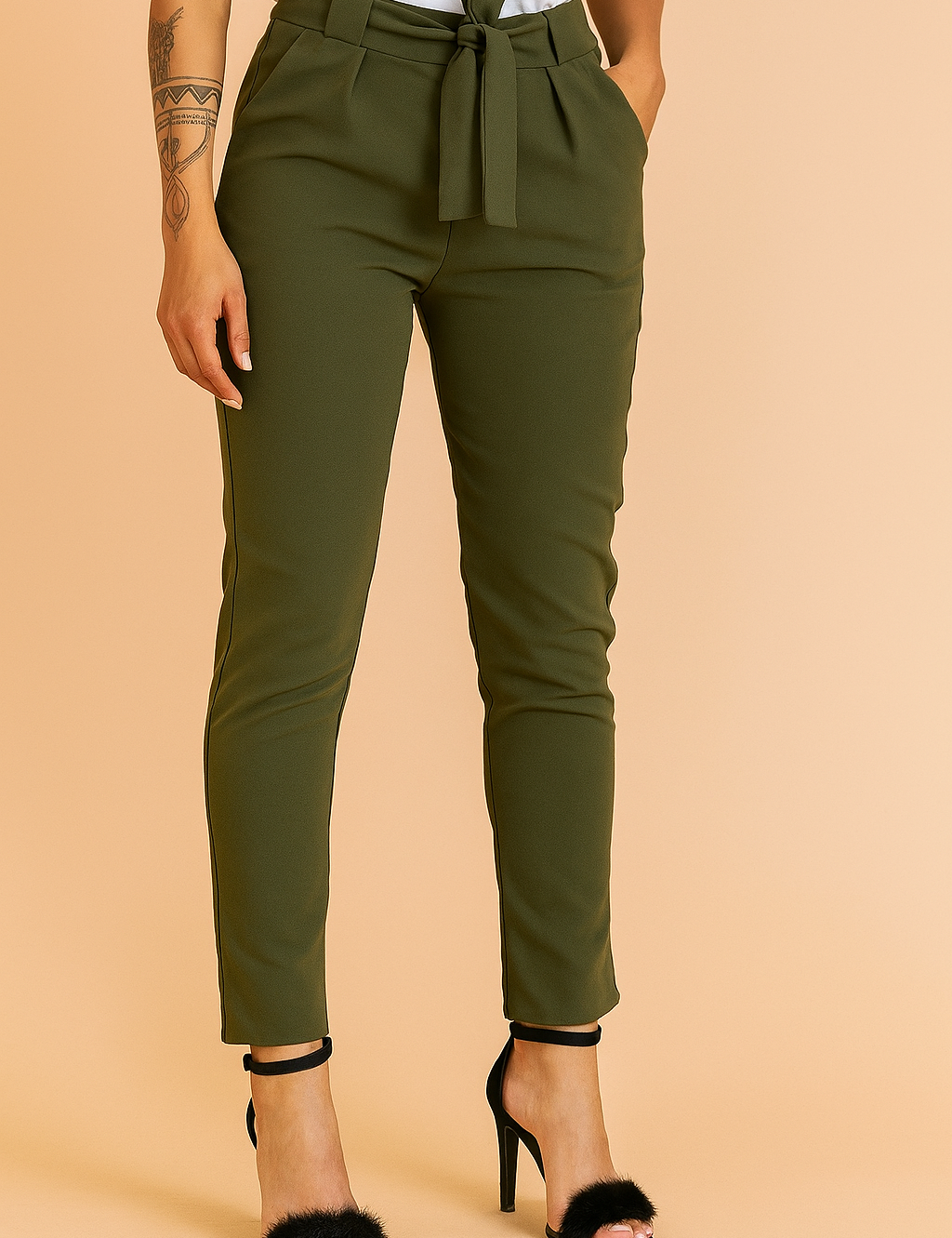 Olive green high-waisted slim-fit trousers with a tie-front belt, pleated detailing, and slanted pockets, styled with black faux fur high-heeled sandals.