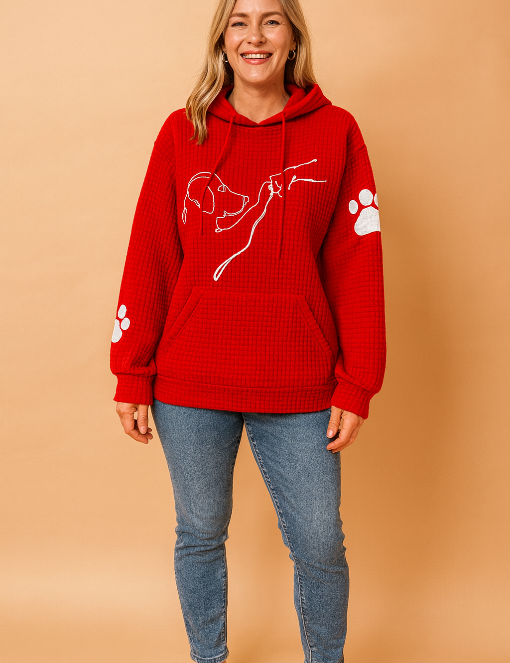 Red waffle-textured hoodie with a white minimalist dog-and-hand line illustration across the chest and white paw print accents on both sleeves, paired with light blue slim-fit jeans and white sneakers.
