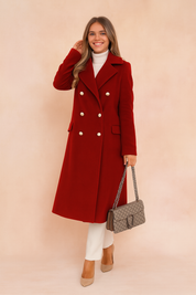 Red double-breasted wool coat with gold buttons, styled with ivory turtleneck, white trousers, beige pumps, and designer handbag