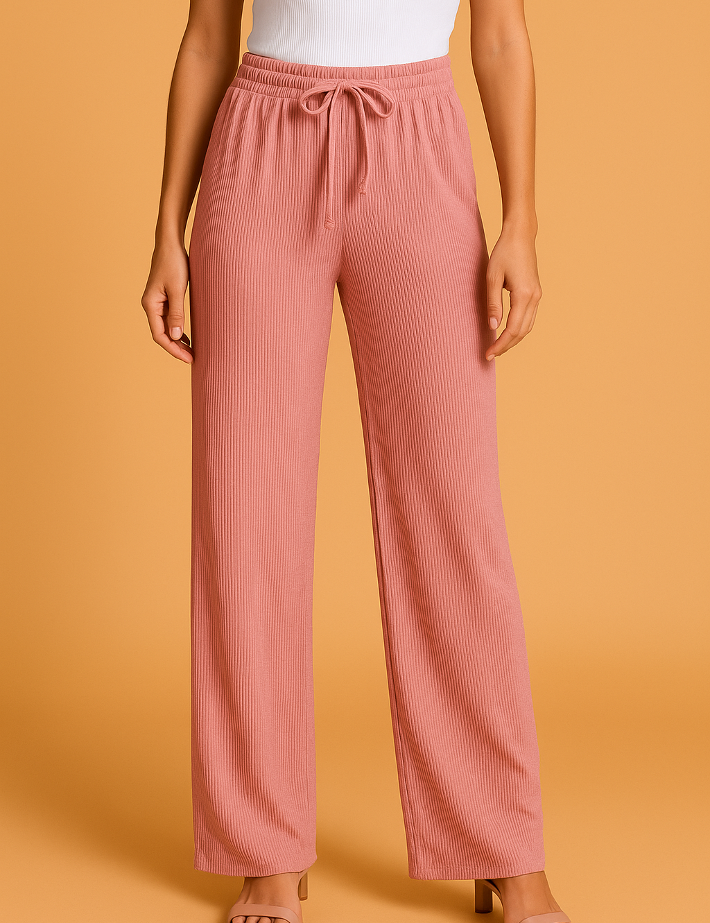 Wide-leg pleated pants in rose pink with a drawstring waistband and vertical rib texture, styled with nude block-heeled sandals and a tucked-in white tank top.