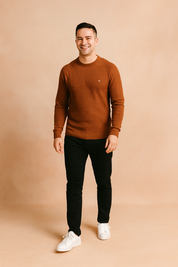 Men’s rust brown textured crewneck sweater with grid knit pattern, styled with slim-fit black jeans and white sneakers.