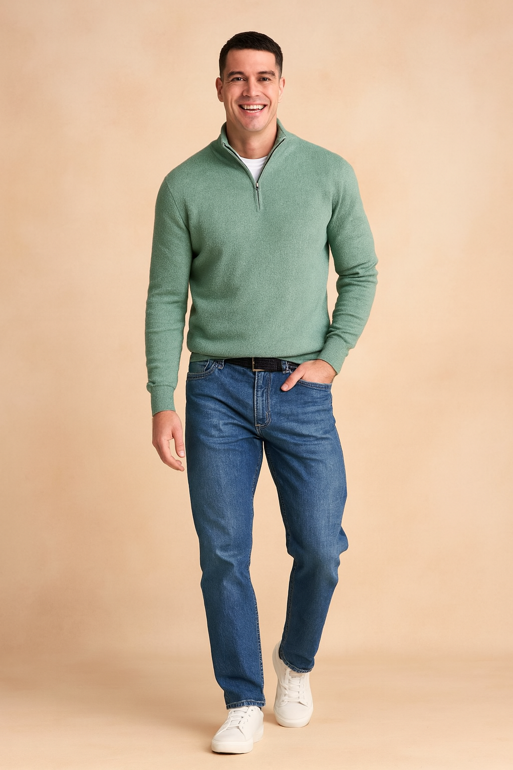 Men’s sage green quarter-zip sweater layered over a white crew-neck t-shirt, styled with blue straight-leg jeans, black leather belt, and white sneakers.