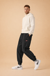 Relaxed-fit corduroy jogger pants with ribbed texture, elastic waistband and cuffs, styled with a minimalist hooded sweatshirt and clean low-top sneakers for a modern casual look.