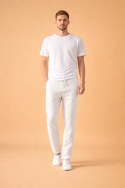 Relaxed slim-fit trousers with an elastic drawstring waist, straight tapered legs, lightweight textured fabric drape, and clean ankle finish, styled with a minimalist short-sleeve top and low-profile lace-up sneakers.