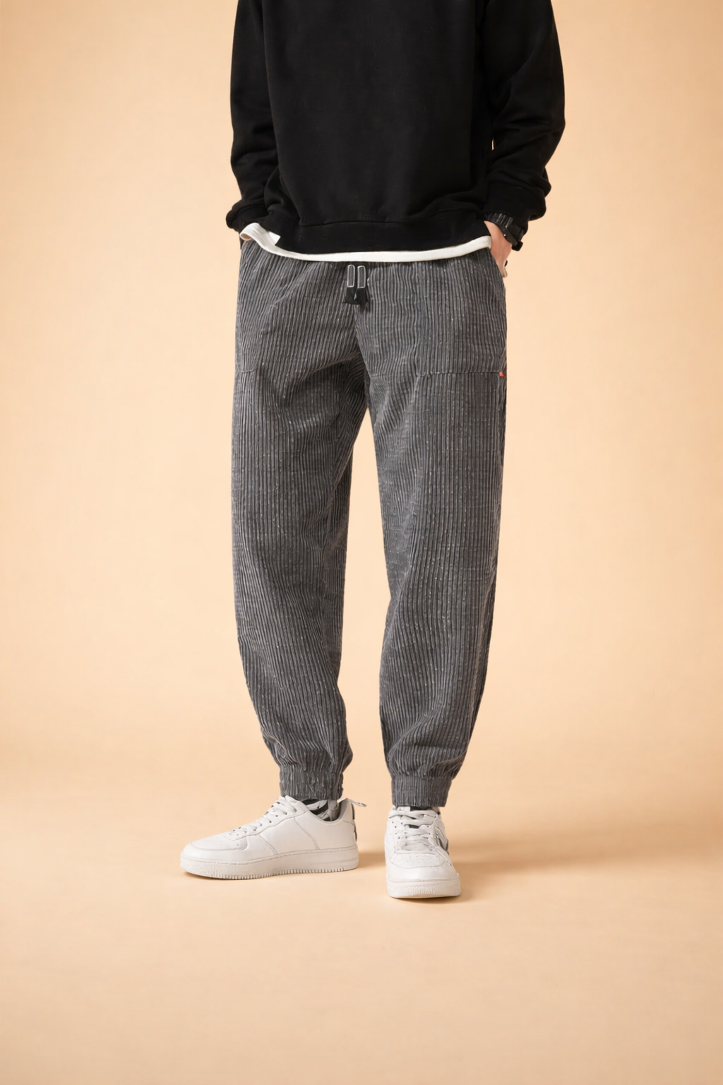 Relaxed-fit grey pinstriped jogger trousers with elasticated cuffs and adjustable drawstring waist, styled with a clean black crewneck sweatshirt and minimalist white low-top sneakers.