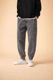 Relaxed-fit grey pinstriped jogger trousers with elasticated cuffs and adjustable drawstring waist, styled with a clean black crewneck sweatshirt and minimalist white low-top sneakers.