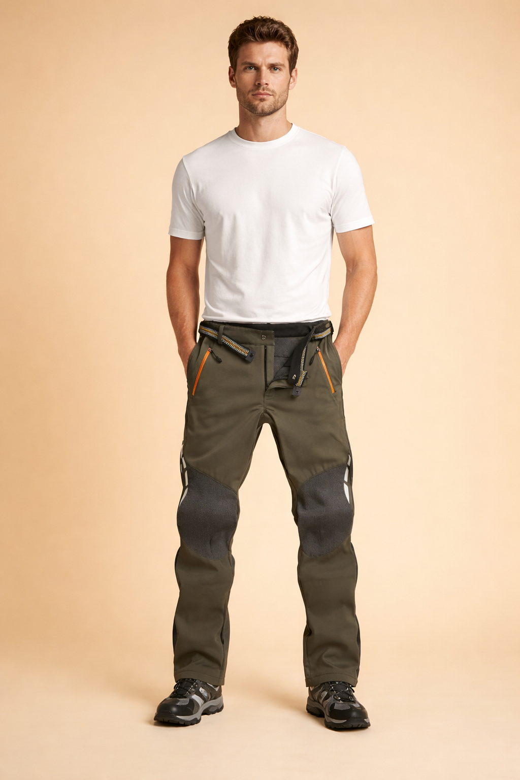 Men’s technical black trousers with reinforced knee panels, articulated leg construction, adjustable waist tabs, front zip pockets with contrast detailing, styled with a fitted short-sleeve top and minimalist low-profile sneakers.