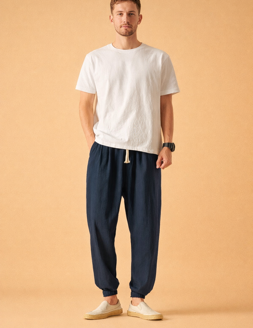 Relaxed-fit elastic waist trousers with tapered legs, adjustable drawstring closure, subtle textured fabric finish, and cuffed ankles, styled with a minimalist short-sleeve top and casual slip-on shoes for a clean everyday look.