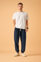 Relaxed-fit elastic waist trousers with tapered legs, adjustable drawstring closure, subtle textured fabric finish, and cuffed ankles, styled with a minimalist short-sleeve top and casual slip-on shoes for a clean everyday look.