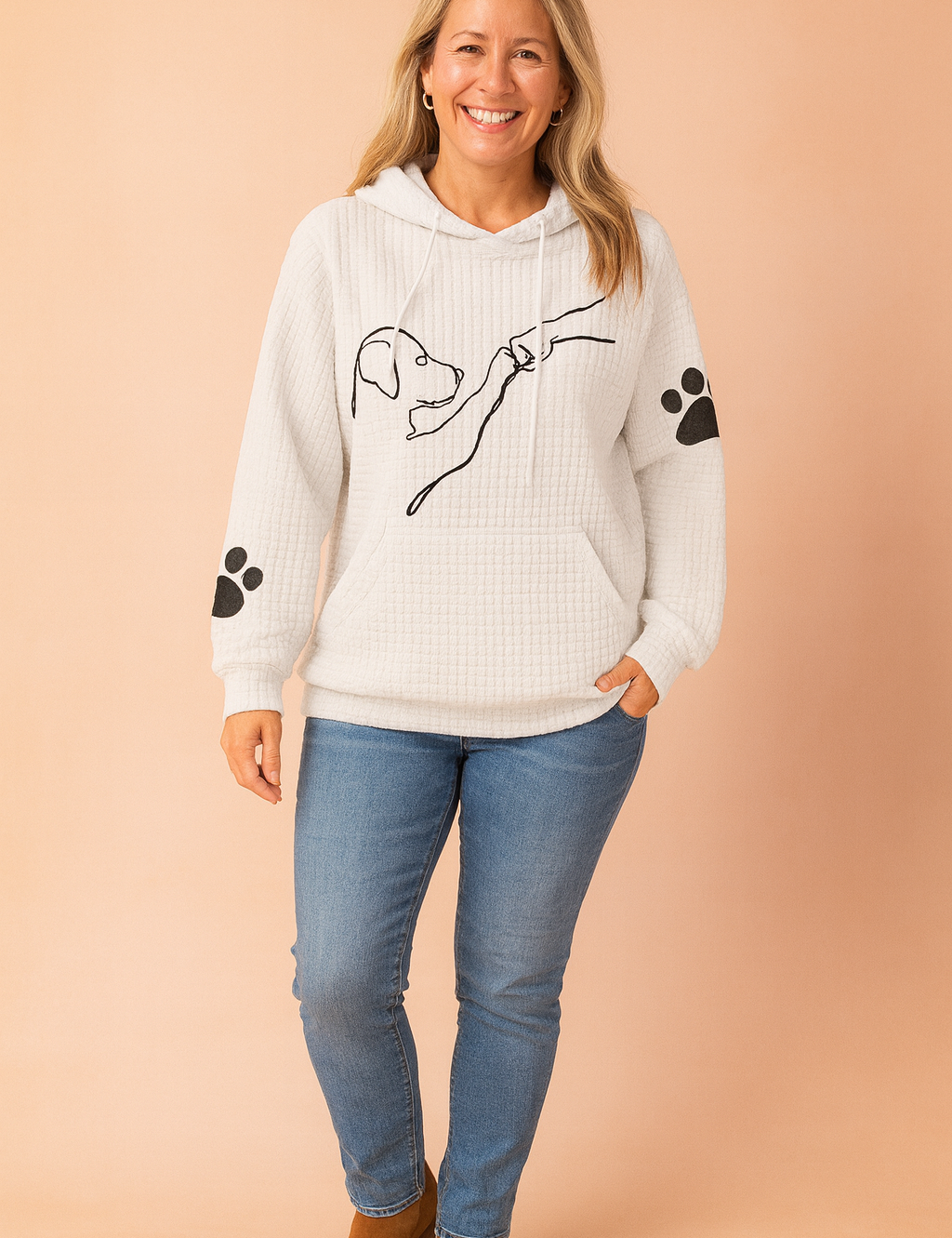White waffle-textured hoodie with black minimalist dog illustration and paw print graphics on sleeves, styled with mid-rise skinny jeans and navy lace-up sneakers.