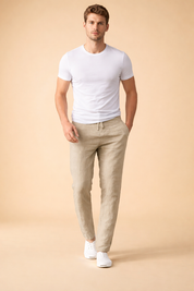 Light beige drawstring trousers with a relaxed straight-leg fit, smooth woven texture, clean waistband tie detail, and a minimalist silhouette styled with a plain white short-sleeve top and white low-profile sneakers.