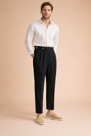 Elegant pleated trousers with a defined high-rise waist, side adjuster detail, front fastening, sharp crease lines, straight-to-tapered silhouette, and ankle-length finish paired with a refined long-sleeve shirt and slip-on loafers.