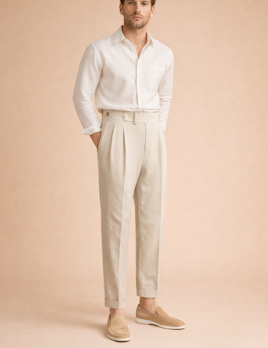 Light-toned pleated trousers featuring a high-rise waistband, front button closure, subtle texture, tailored leg shape, and cuffed ankle length styled with a lightweight long-sleeve shirt and clean loafers.