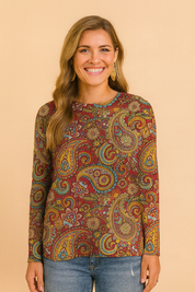 Long-sleeve paisley-print blouse in vibrant red, yellow, blue, and green tones, paired with fitted blue jeans and white sneakers.