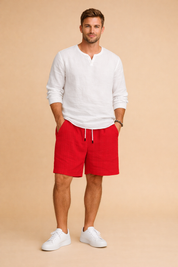 Red ribbed summer shorts with an elastic drawstring waist and side pockets, styled with a clean white long-sleeve shirt and minimalist low-profile sneakers for a refined casual look, showcasing the exact ribbed fabric texture, precise red color shade, and original cut of the shorts.