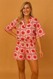 Red and white graphic print two-piece co-ord set featuring a relaxed button-up shirt with short sleeves and matching drawstring shorts, designed for a bold and playful summer look.