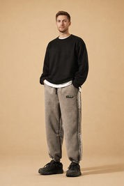 Relaxed-fit tapered jogger pants with elasticated cuffs, straight leg silhouette, soft textured finish, adjustable drawstring waist, and subtle side detailing paired with low-profile athletic footwear.