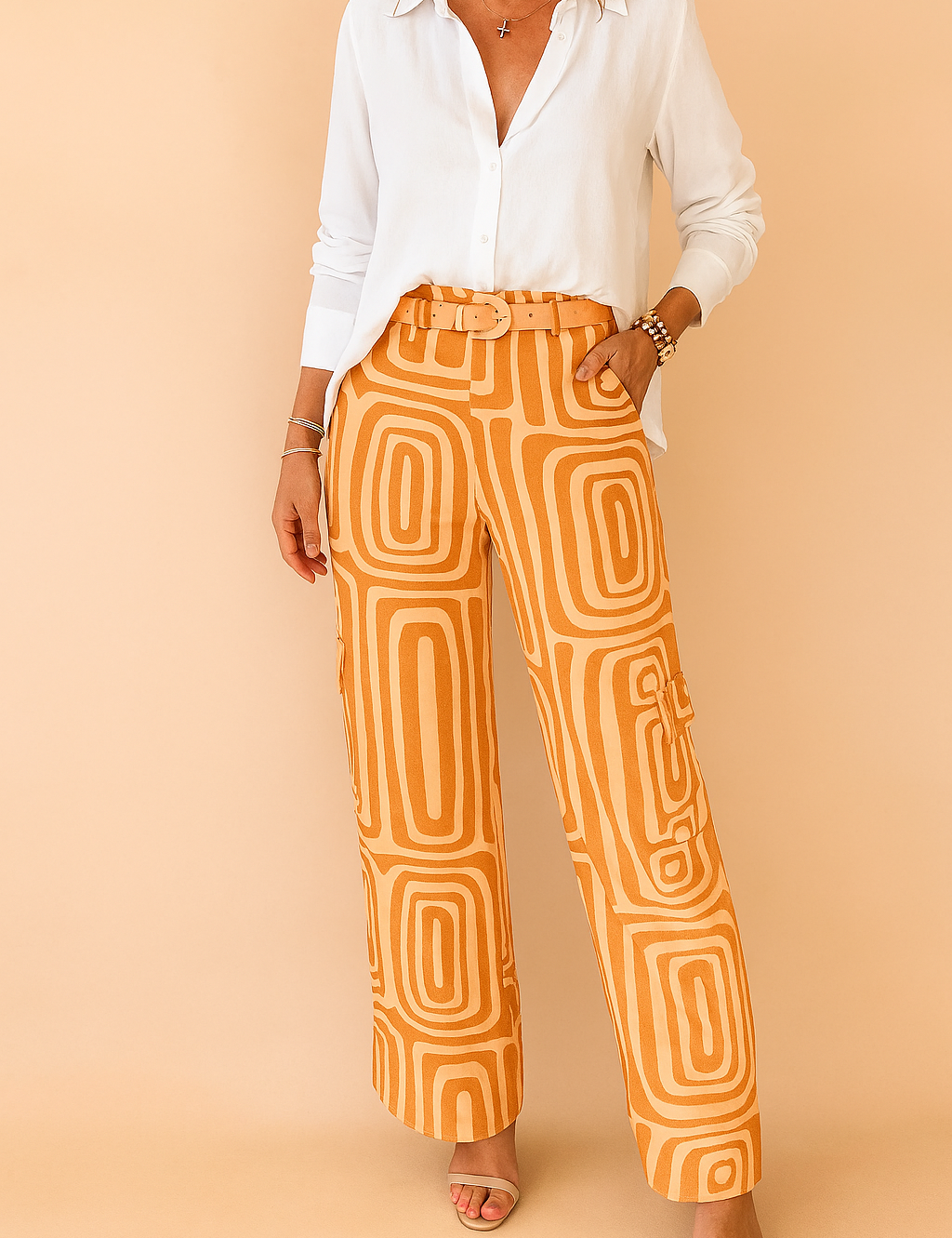 High-waisted orange wide-leg pants with a retro geometric pattern and matching fabric belt, styled with a relaxed white button-up blouse and open-toe nude sandals for a chic modern look