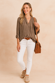 Dark charcoal button-up blouse with vertical white stripes, featuring rolled sleeves and a relaxed fit, paired with fitted white pants and a brown belt.