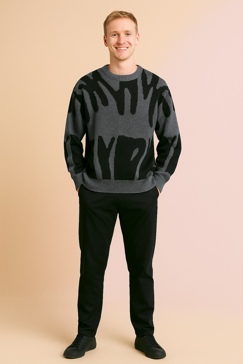 Gray crewneck sweater with bold abstract black patterns, soft knit fabric, relaxed fit, styled with black trousers and black sneakers.