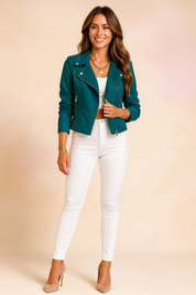 Teal biker jacket with silver button and zipper details, styled over a white cropped top and paired with high-waisted white pants and beige pumps.