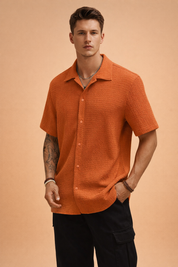 Textured short-sleeve button-up shirt with a relaxed open collar, straight hem, and clean front placket, styled with black tailored trousers for a modern casual look.