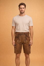 Traditional brown suede leather lederhosen shorts with ornate alpine embroidery, decorative front flap, classic side pockets, and an adjustable leather belt with an engraved metal buckle.