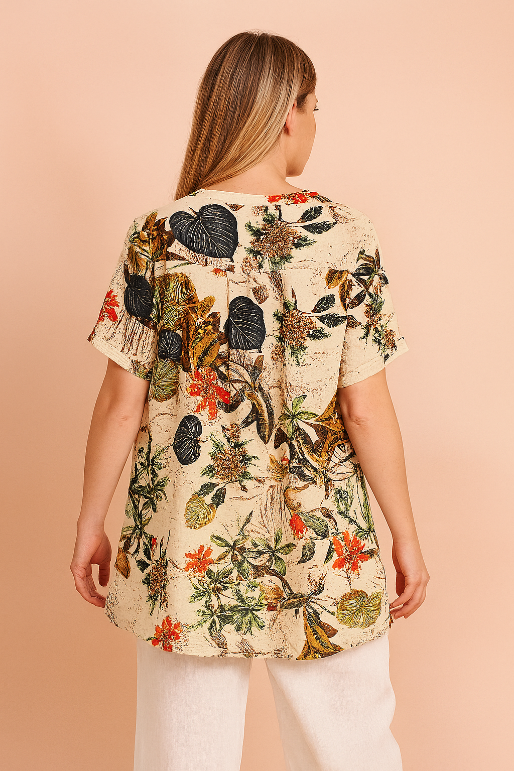 tropical floral tunic top featuring a cream background with vibrant leaf and blossom prints, styled with white linen pants—ideal for casual summer fashion.