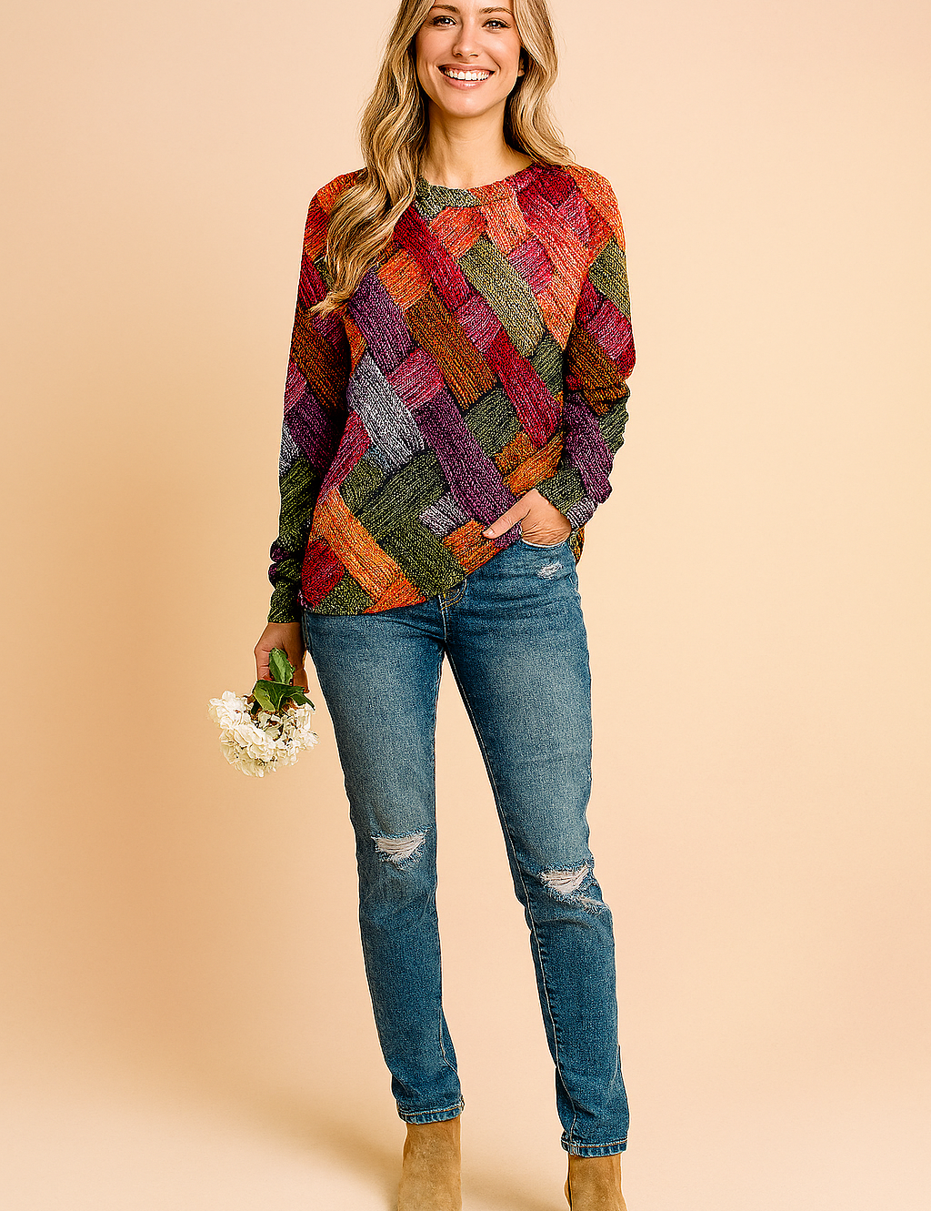 Colorful patchwork-print long-sleeve pullover sweater with a diamond pattern in red, orange, yellow, pink, and brown tones, paired with distressed blue jeans.