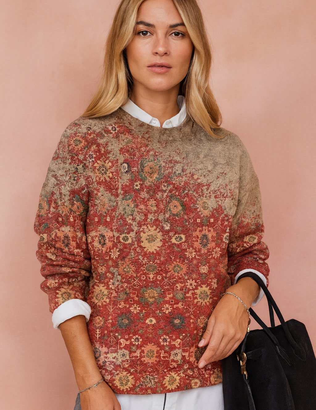  Vintage-inspired crewneck sweater with a faded red floral tapestry pattern, paired with a white button-up shirt layered underneath and accessorized with a black suede handbag.
