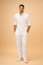 Textured white long-sleeve henley shirt with subtle woven fabric pattern, band collar and button placket, paired with relaxed-fit white trousers and clean minimalist white low-top sneakers for a refined summer casual look.